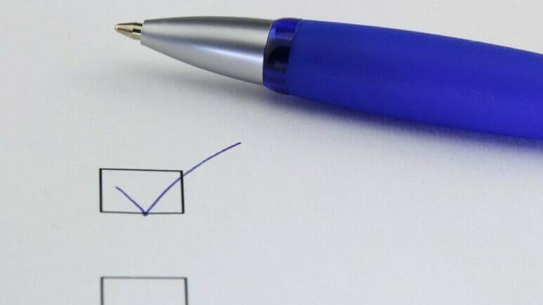 piece of paper with checkboxes and a blue pen sitting next to a checked box