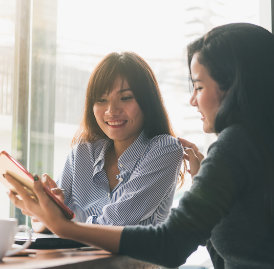 Two women talking while looking at a phone